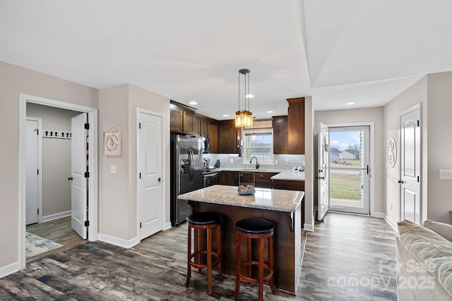 kitchen with sink, stainless steel fridge, hanging light fixtures, a center island, and tasteful backsplash