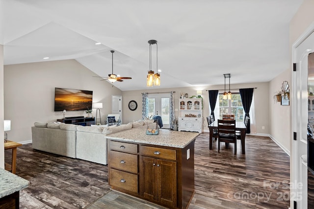 kitchen featuring hanging light fixtures, light stone countertops, dark hardwood / wood-style flooring, vaulted ceiling, and french doors