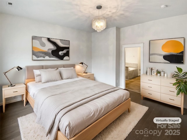 bedroom featuring ensuite bath, dark wood-type flooring, and a chandelier