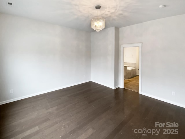 unfurnished room with dark hardwood / wood-style floors and a chandelier