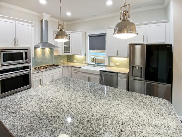 kitchen featuring stainless steel appliances, white cabinetry, pendant lighting, and wall chimney exhaust hood