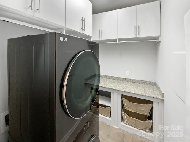 laundry area with light tile patterned floors and cabinets