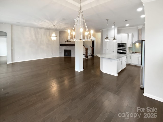 kitchen featuring decorative light fixtures, tasteful backsplash, white cabinets, a center island, and stainless steel appliances