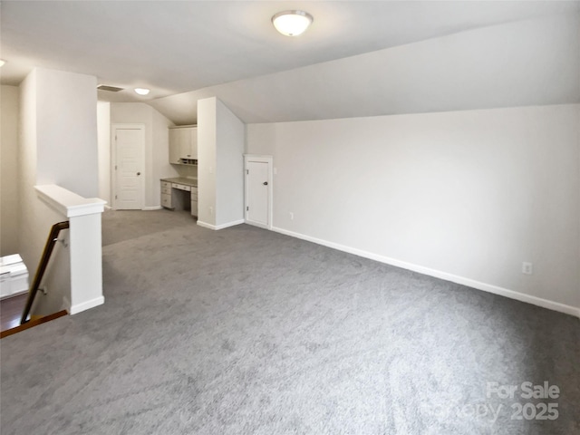 additional living space featuring lofted ceiling and dark colored carpet