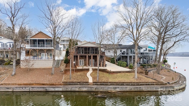 back of house with a sunroom, a patio, and a water view