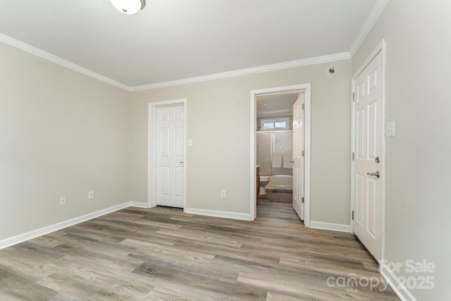 unfurnished bedroom with crown molding, connected bathroom, and hardwood / wood-style flooring