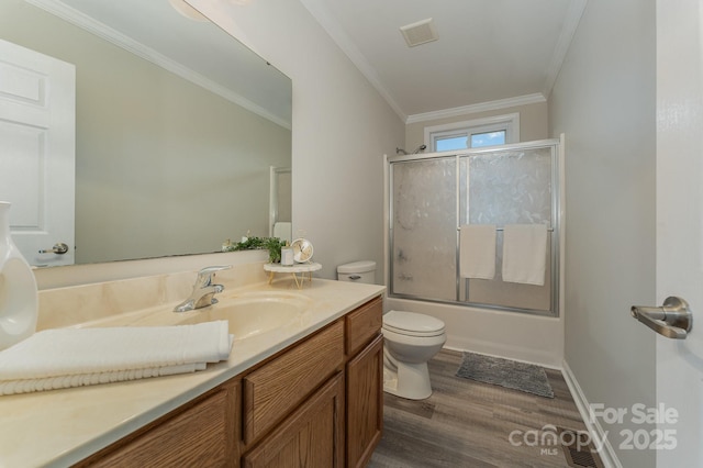 full bathroom with hardwood / wood-style floors, shower / bath combination with glass door, ornamental molding, vanity, and toilet