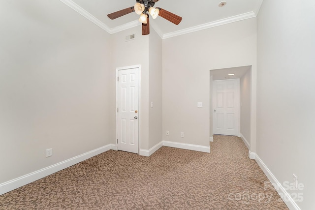 carpeted spare room featuring crown molding, ceiling fan, and a high ceiling