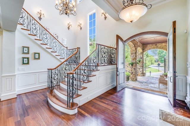 entryway featuring hardwood / wood-style flooring, ornamental molding, a chandelier, and a high ceiling