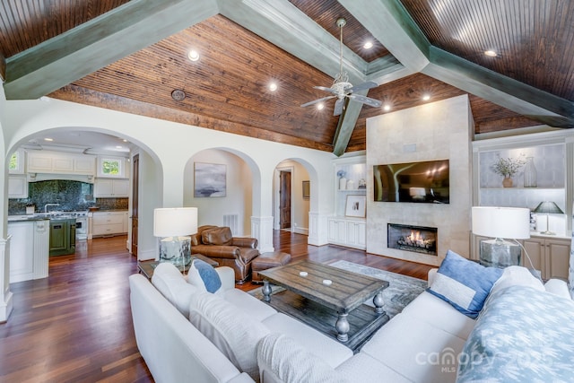 living room with dark wood-type flooring, a large fireplace, built in shelves, and wooden ceiling