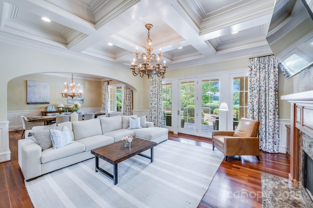 living room with crown molding, a premium fireplace, an inviting chandelier, beam ceiling, and coffered ceiling