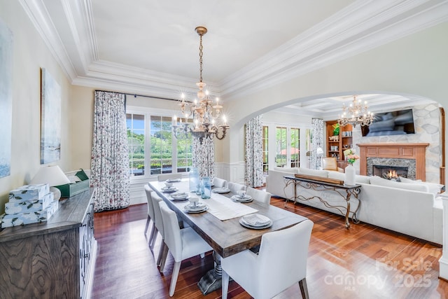 dining space featuring built in shelves, ornamental molding, a notable chandelier, hardwood / wood-style flooring, and a high end fireplace