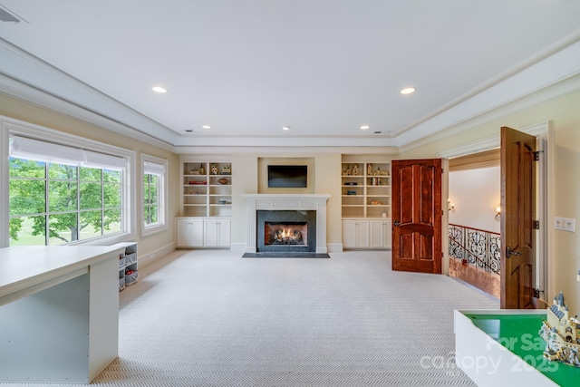 living room featuring a premium fireplace, light carpet, built in features, and crown molding