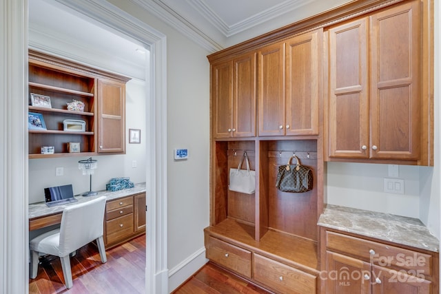 mudroom with light hardwood / wood-style flooring, built in desk, and ornamental molding