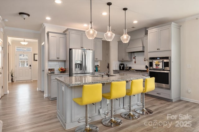 kitchen with light stone counters, stainless steel appliances, a kitchen breakfast bar, and a center island with sink