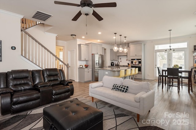 living room with sink, ceiling fan with notable chandelier, light hardwood / wood-style flooring, and ornamental molding