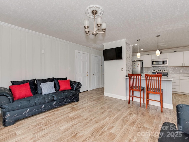 living room featuring crown molding, an inviting chandelier, light hardwood / wood-style floors, and a textured ceiling