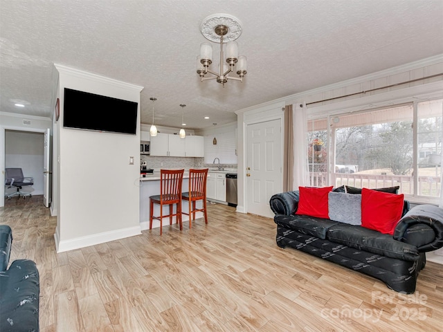 living room featuring sink, a notable chandelier, light hardwood / wood-style floors, crown molding, and a textured ceiling