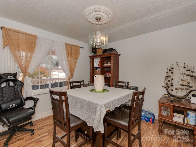 dining area featuring an inviting chandelier, a textured ceiling, and light wood-type flooring