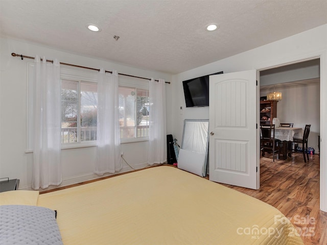 bedroom featuring an inviting chandelier, hardwood / wood-style floors, and a textured ceiling