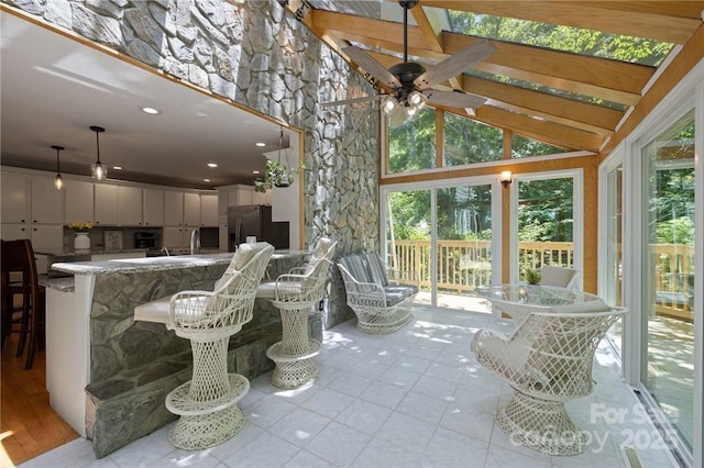 sunroom with ceiling fan and vaulted ceiling