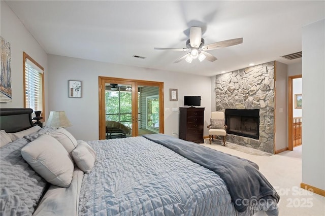 bedroom with ceiling fan, a stone fireplace, access to outside, light colored carpet, and french doors