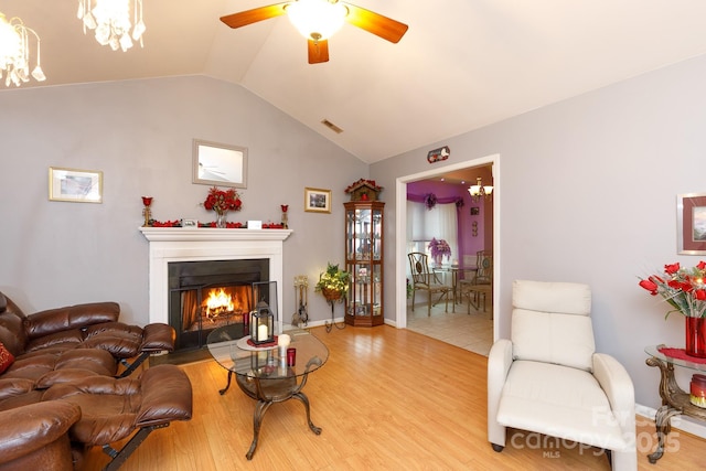 living room with vaulted ceiling, ceiling fan with notable chandelier, and light hardwood / wood-style floors