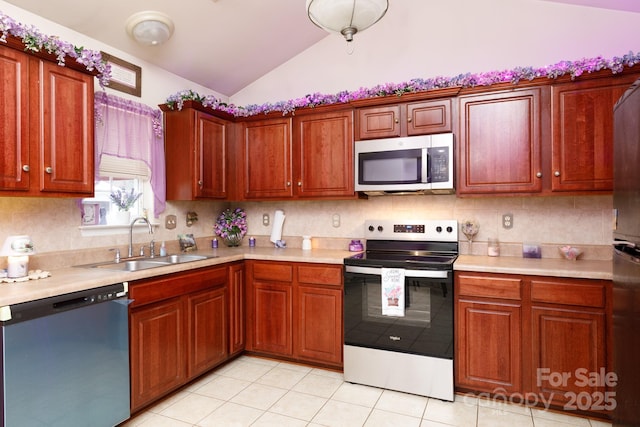 kitchen featuring sink, vaulted ceiling, light tile patterned floors, appliances with stainless steel finishes, and backsplash