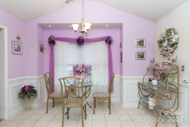 tiled dining room featuring lofted ceiling and a chandelier