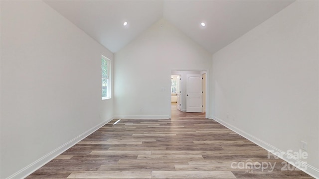 empty room with baseboards, recessed lighting, high vaulted ceiling, and wood finished floors