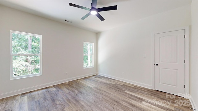 spare room featuring baseboards, ceiling fan, light wood finished floors, and visible vents