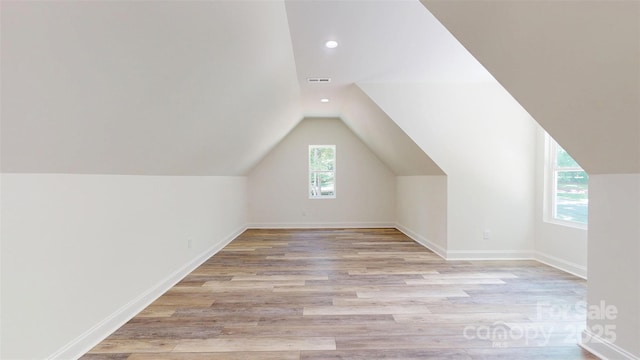 additional living space with light wood-type flooring, baseboards, lofted ceiling, and recessed lighting