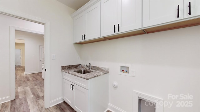 clothes washing area with a sink, cabinet space, light wood-type flooring, baseboards, and hookup for a washing machine