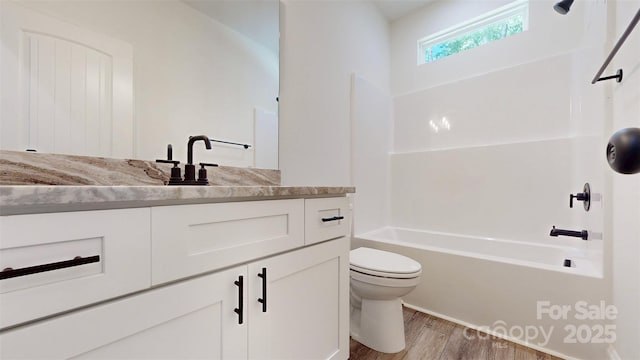 bathroom featuring toilet, vanity, shower / tub combination, and wood finished floors