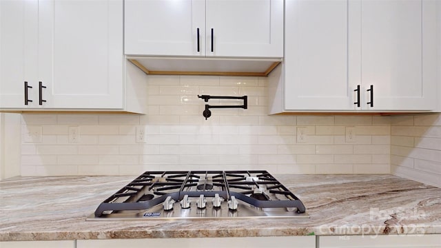 kitchen with white cabinets, stainless steel gas stovetop, and decorative backsplash