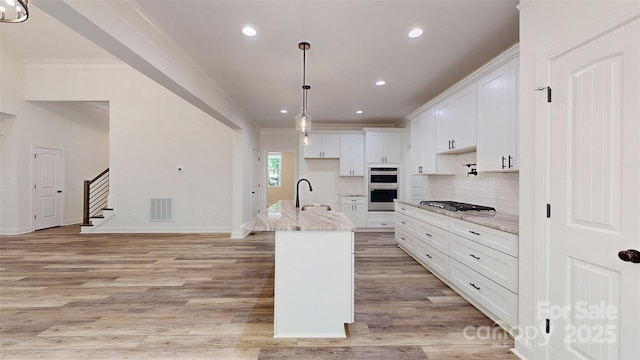 kitchen featuring a sink, stainless steel appliances, crown molding, light wood-type flooring, and white cabinetry