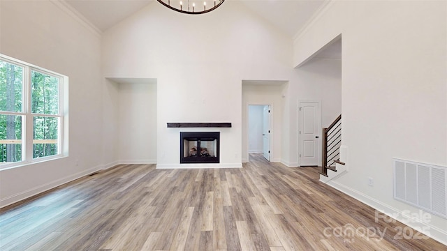 unfurnished living room featuring high vaulted ceiling, a wealth of natural light, visible vents, and stairs