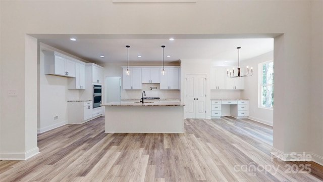 kitchen featuring baseboards, light wood finished floors, stainless steel double oven, decorative backsplash, and white cabinets