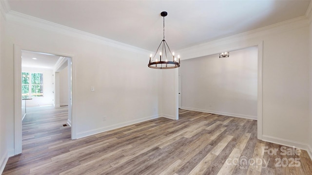 unfurnished dining area featuring ornamental molding, light wood-style floors, a chandelier, and baseboards