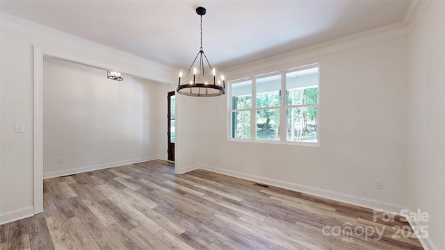 unfurnished room with baseboards, an inviting chandelier, crown molding, and wood finished floors