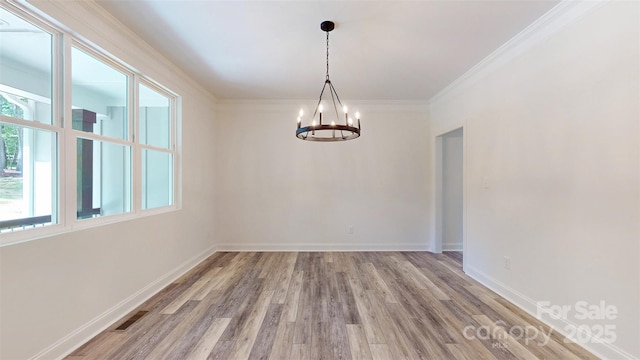 empty room featuring ornamental molding, visible vents, a chandelier, baseboards, and light wood-style floors