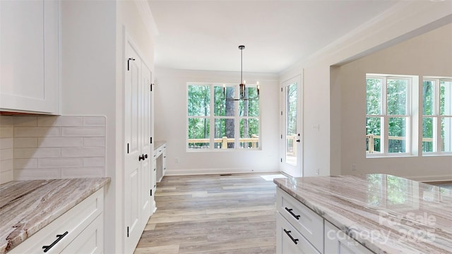 4607 Ferguson Cir, Waxhaw, NC 28173 - dining room with baseboards, light wood-style floors, an inviting chandelier, and ornamental molding