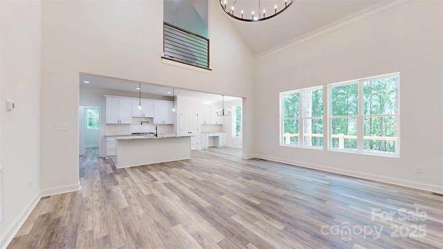 4607 Ferguson Cir, Waxhaw, NC 28173 - living area featuring light wood-type flooring, a notable chandelier, crown molding, and high vaulted ceiling