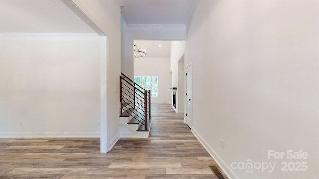 4607 Ferguson Cir, Waxhaw, NC 28173 - hall with a notable chandelier, light wood-style flooring, baseboards, ornamental molding, and stairway