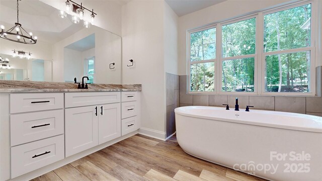 4607 Ferguson Cir, Waxhaw, NC 28173 - bathroom with a notable chandelier, a healthy amount of sunlight, a freestanding bath, and wood finished floors