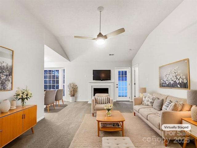 carpeted living room with ceiling fan and vaulted ceiling