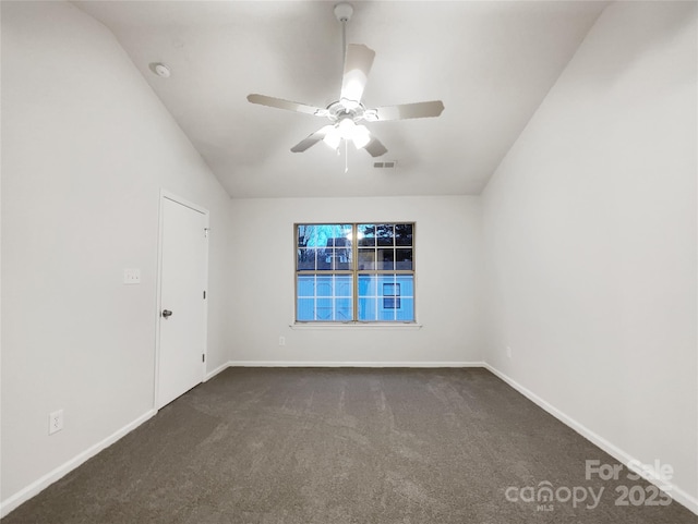 empty room featuring ceiling fan, vaulted ceiling, and dark carpet