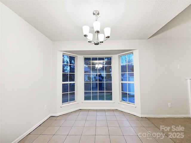 unfurnished dining area featuring light tile patterned floors, a textured ceiling, and an inviting chandelier