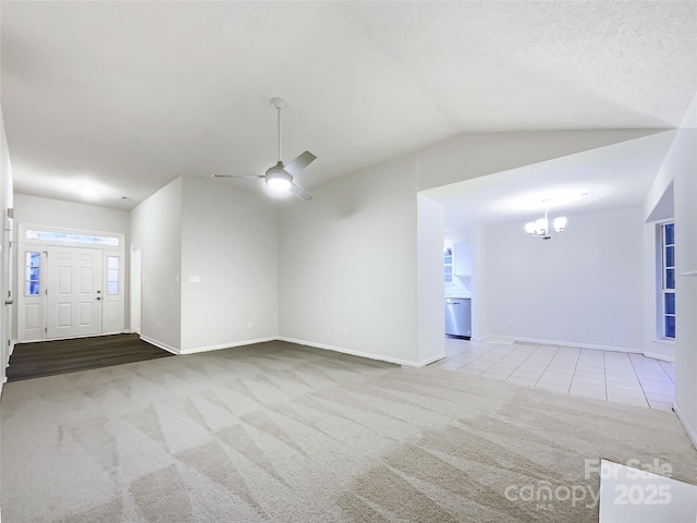 unfurnished living room with vaulted ceiling, ceiling fan with notable chandelier, light colored carpet, and a textured ceiling