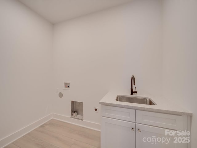 laundry area featuring sink, electric dryer hookup, hookup for a washing machine, cabinets, and light hardwood / wood-style floors